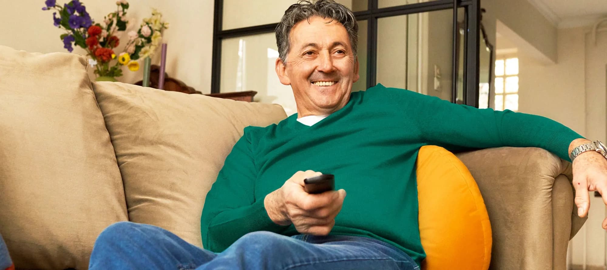 Man met een afstandsbediening kijkt tv op de bank